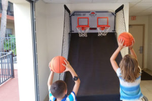 two kids playing a basketball arcade game