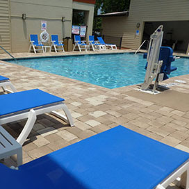 outdoor swimming pool with lounge chairs around and pool lift