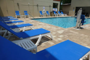 outdoor swimming pool with lounge chairs around and pool lift